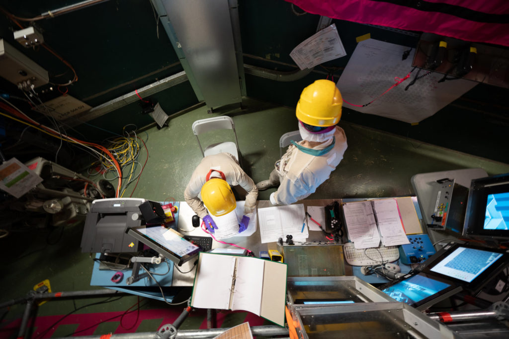 deux hommes en habits de travail commande un reacteur nucleaire